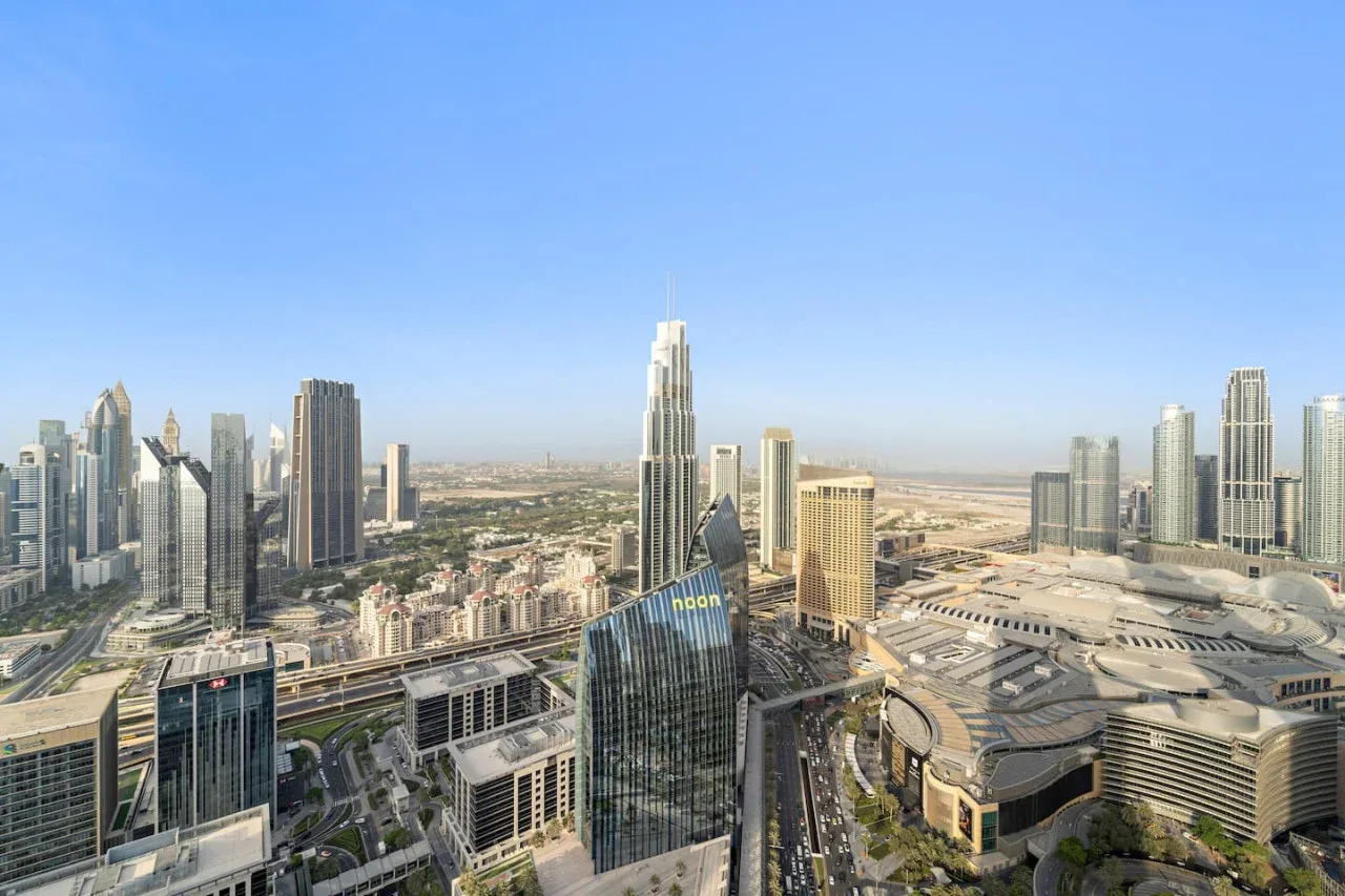 Un horizonte urbano con edificios altos y carreteras bajo un cielo azul despejado.