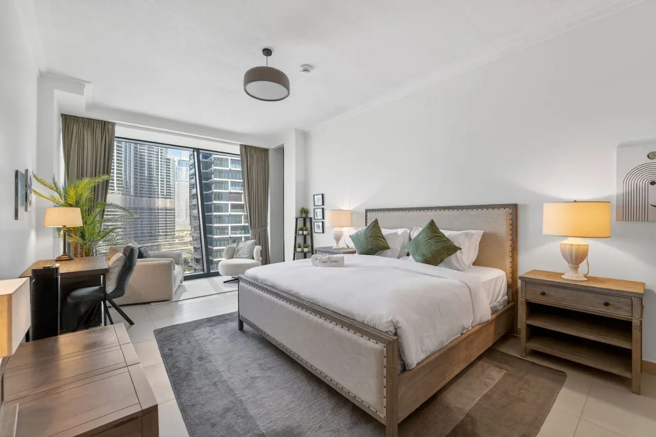 A bedroom with a large bed, bedside tables, and a window overlooking nearby buildings.