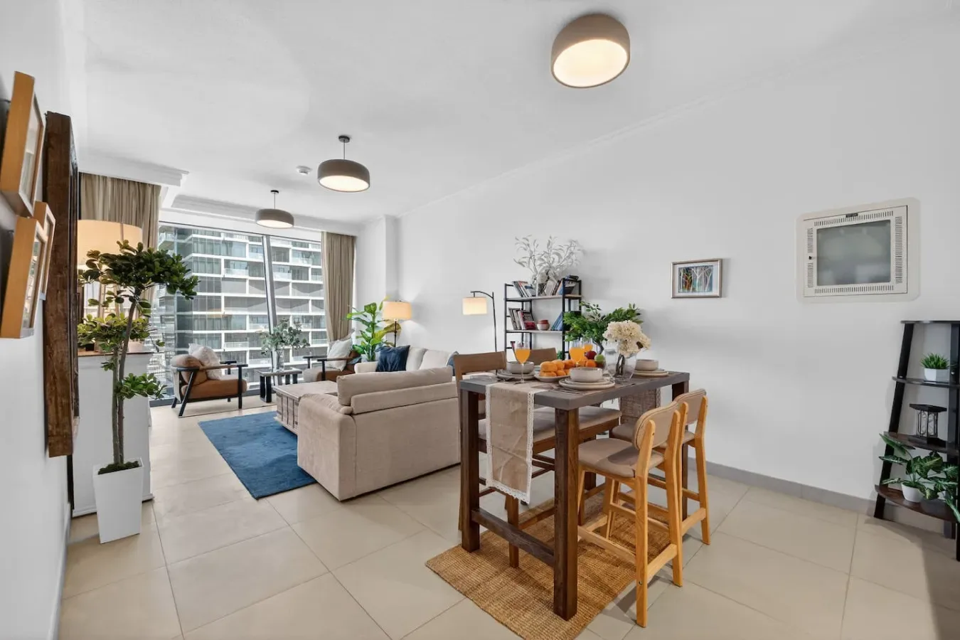 A bright living and dining area with a sofa, table, and large windows.