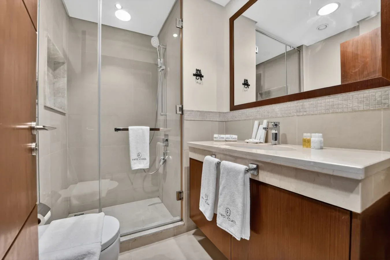 A modern bathroom with a glass shower, toilet, and long vanity.