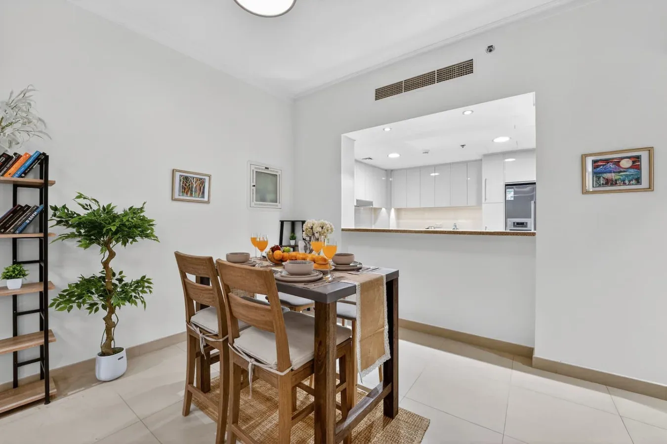 A dining area with a wooden table and seating beside an open kitchen.