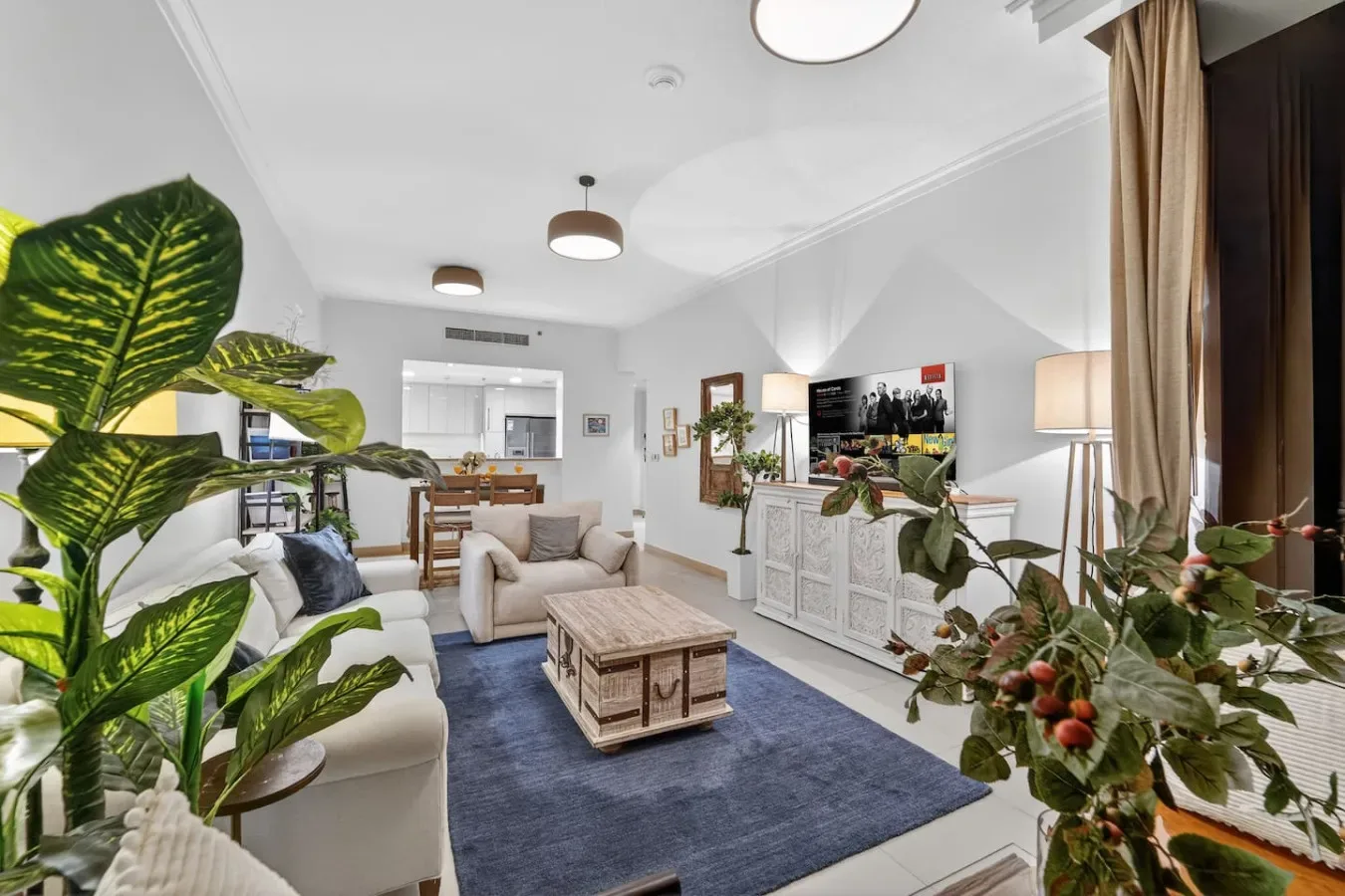 A bright living room with seating around a wooden coffee table and a television.