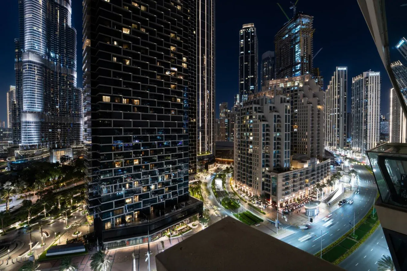 A nighttime cityscape with illuminated high-rise buildings and streets.