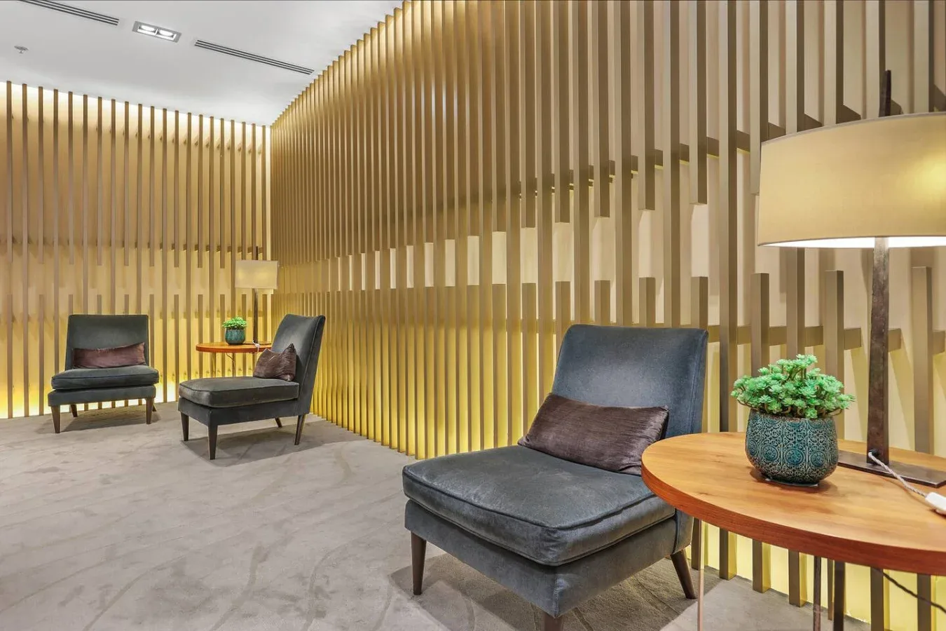 A modern lounge with dark seating, a round table, and vertical wooden slats.