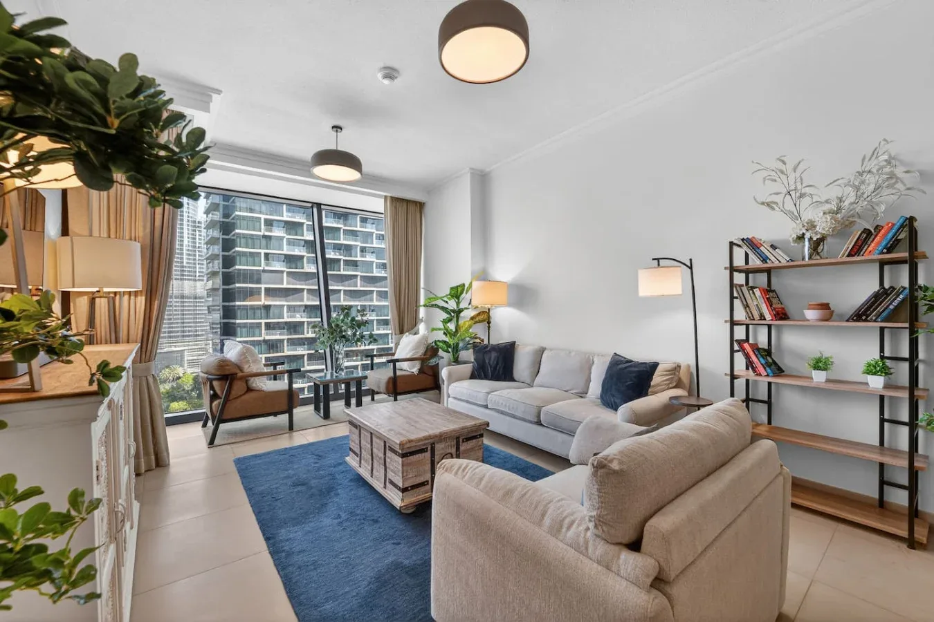 A bright living room with seating around a coffee table beside large windows.