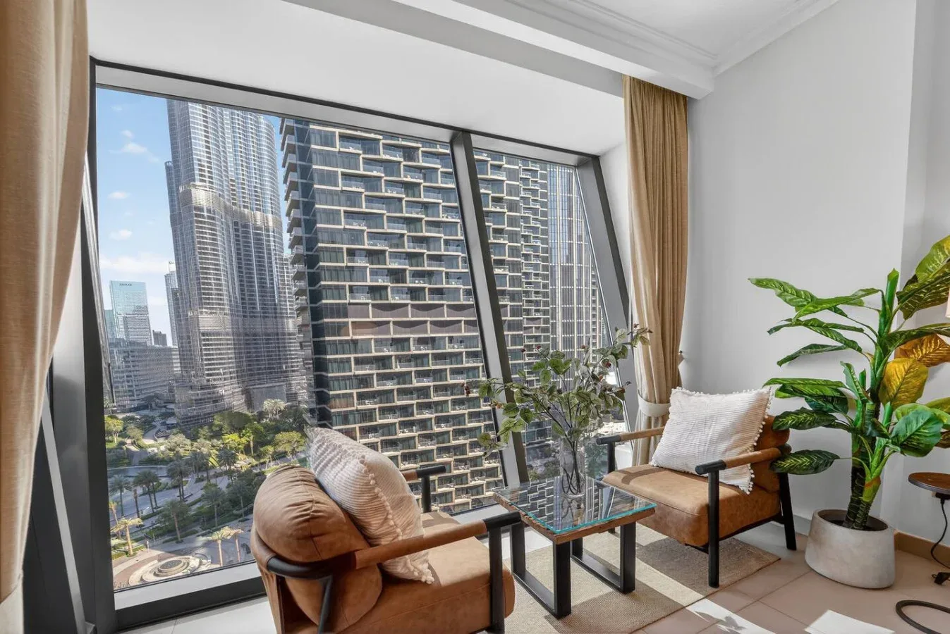 A bright sitting area beside large windows overlooks nearby city buildings.