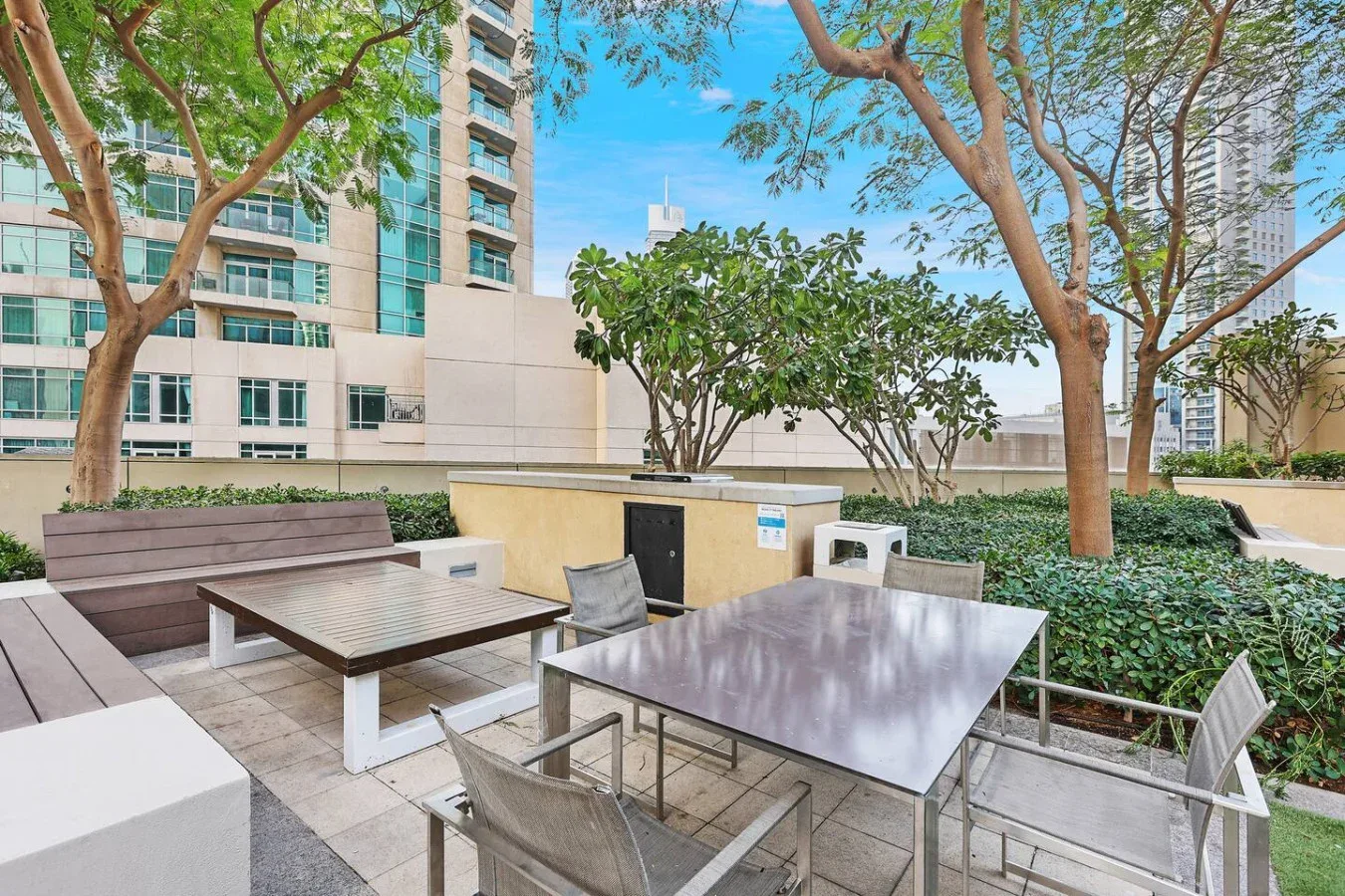 An outdoor seating area with tables, chairs, and trees.