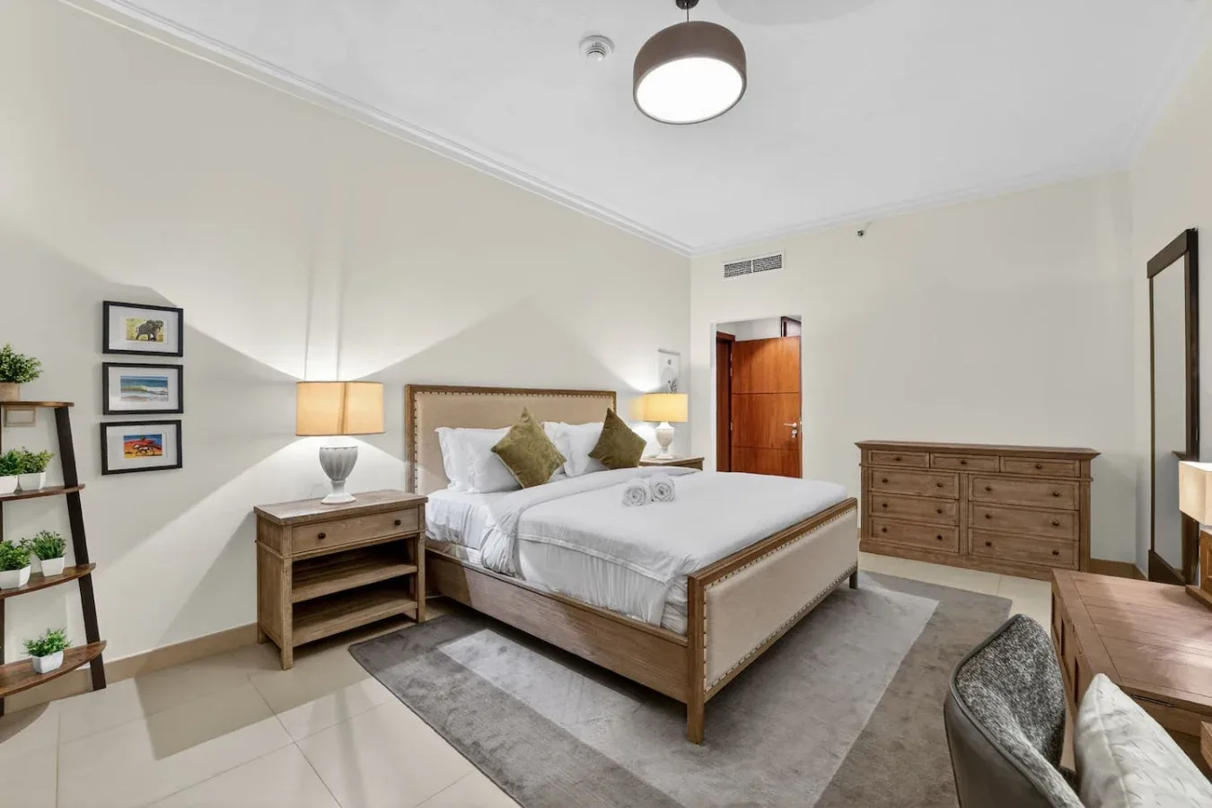 A bedroom with a neatly made bed, bedside tables, and a wooden dresser.