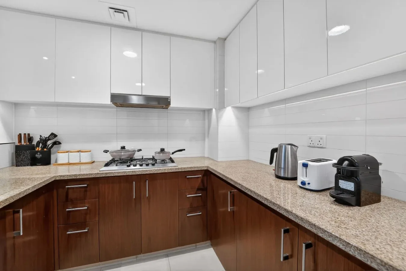 A modern kitchen with L-shaped counters, upper cabinets, and countertop appliances.