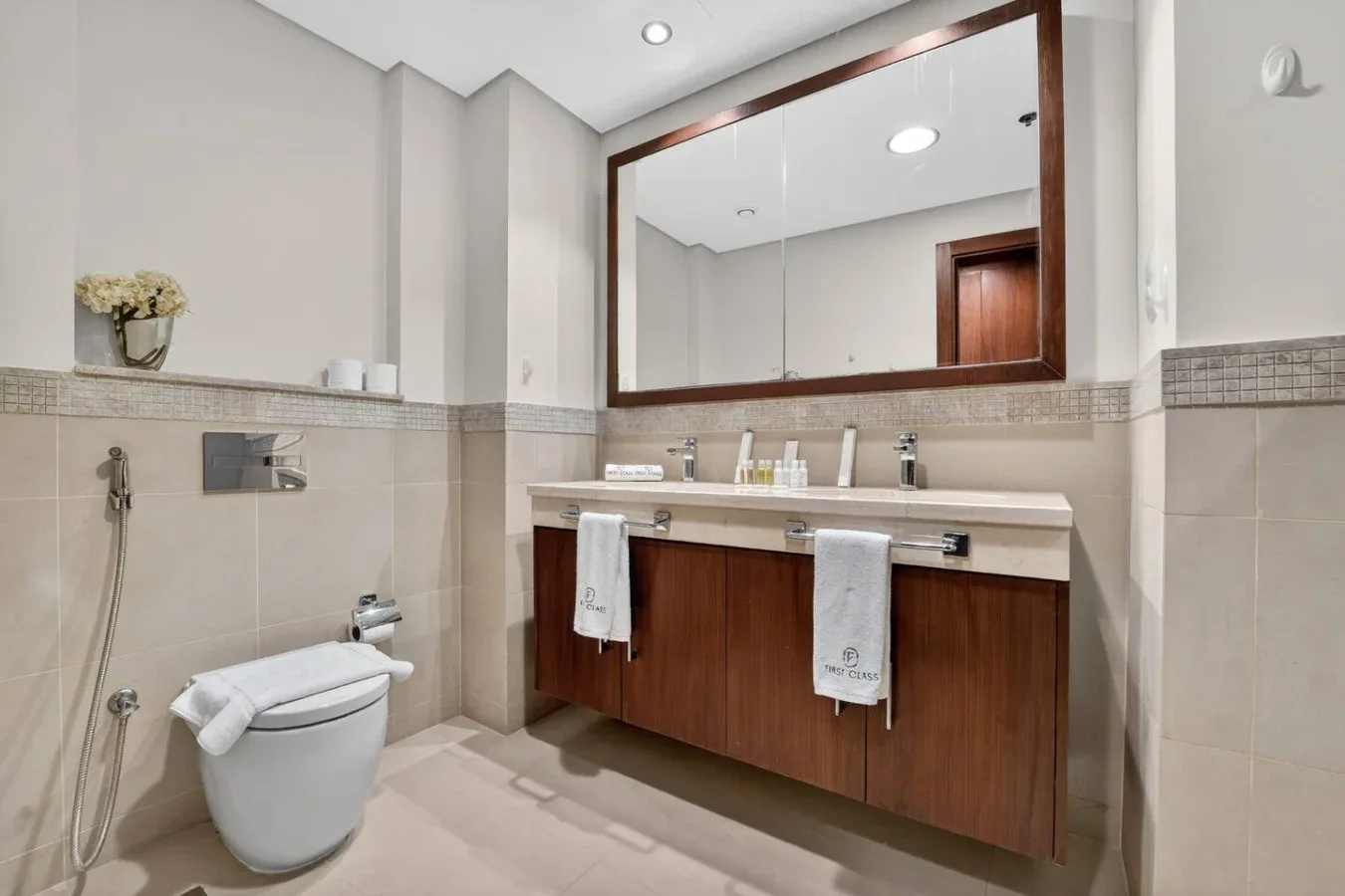A bathroom with a wide vanity and a toilet beside the shower controls.