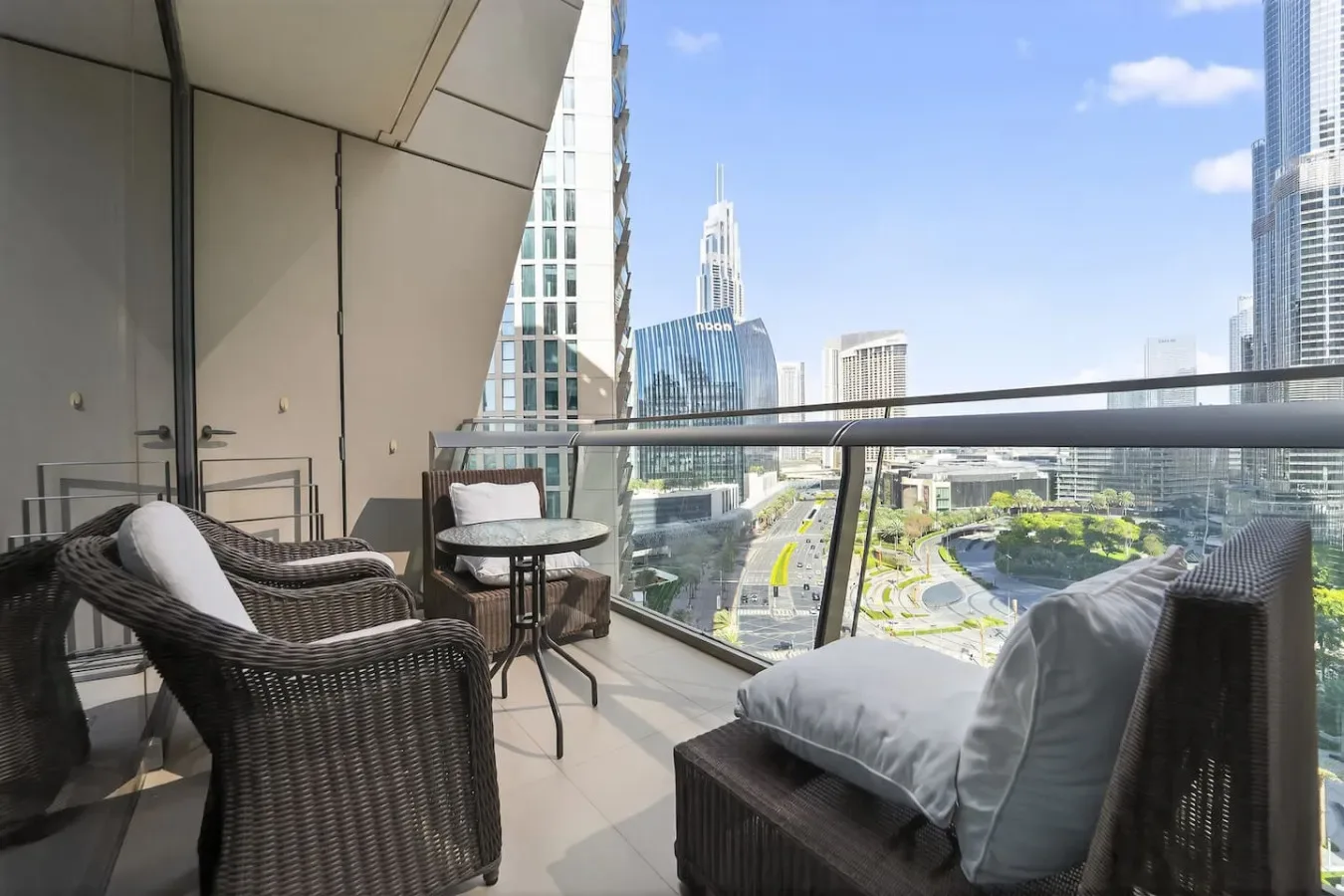 A balcony seating area overlooks a city skyline and landscaped roads.