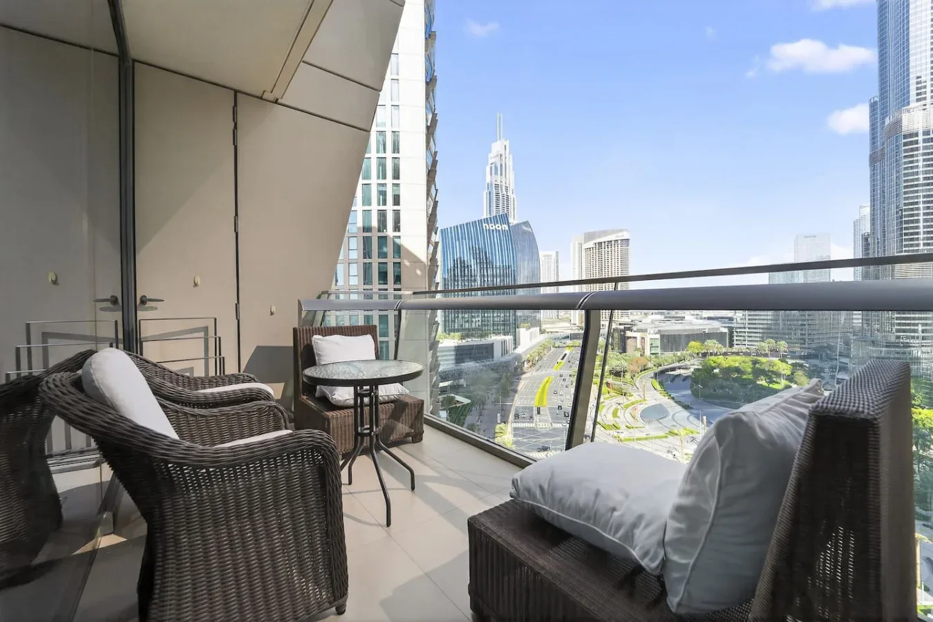 A balcony seating area overlooks a city skyline through a glass railing.