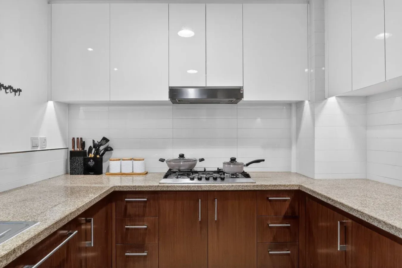 A kitchen with wooden cabinets, a cooktop, and pots on the counter.
