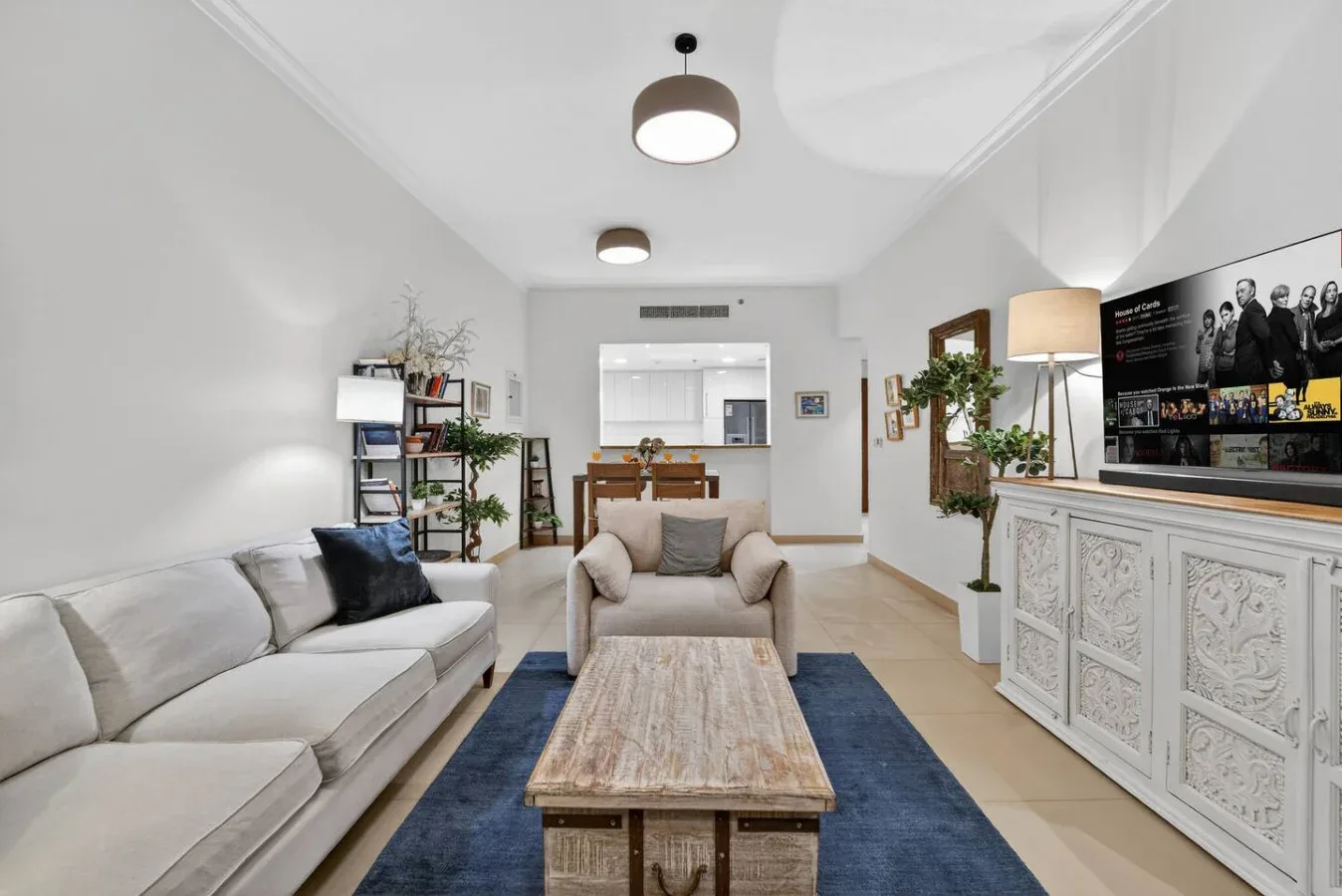 A bright living room with seating, a coffee table, and a television.