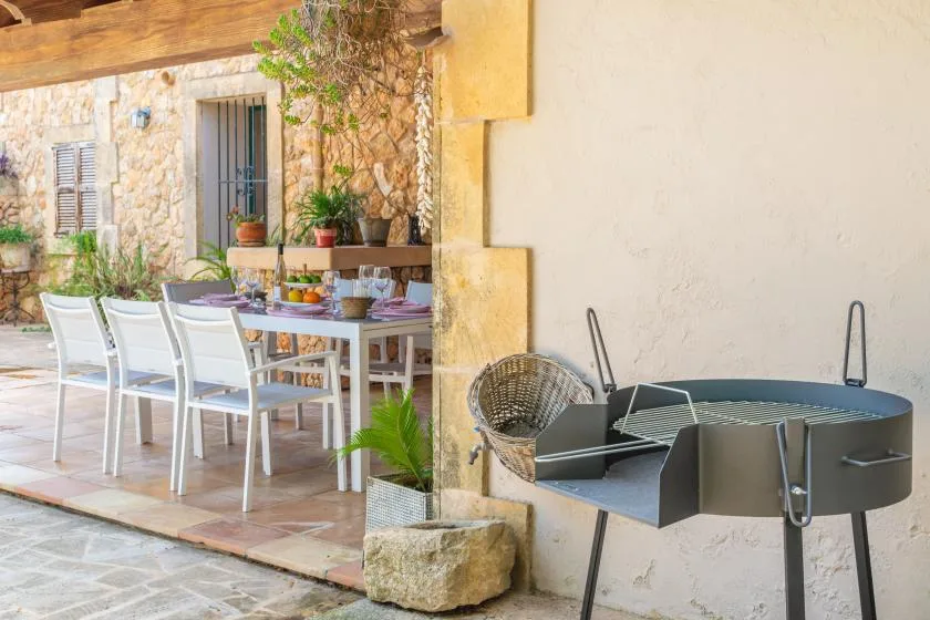 An outdoor dining area with a table and chairs beside a stone wall.