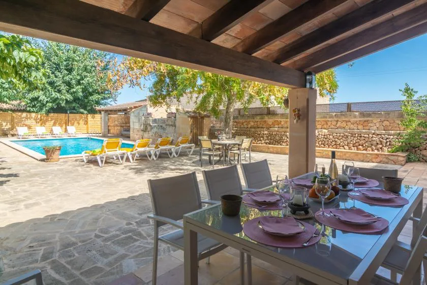 A covered outdoor dining area overlooks a patio and swimming pool.