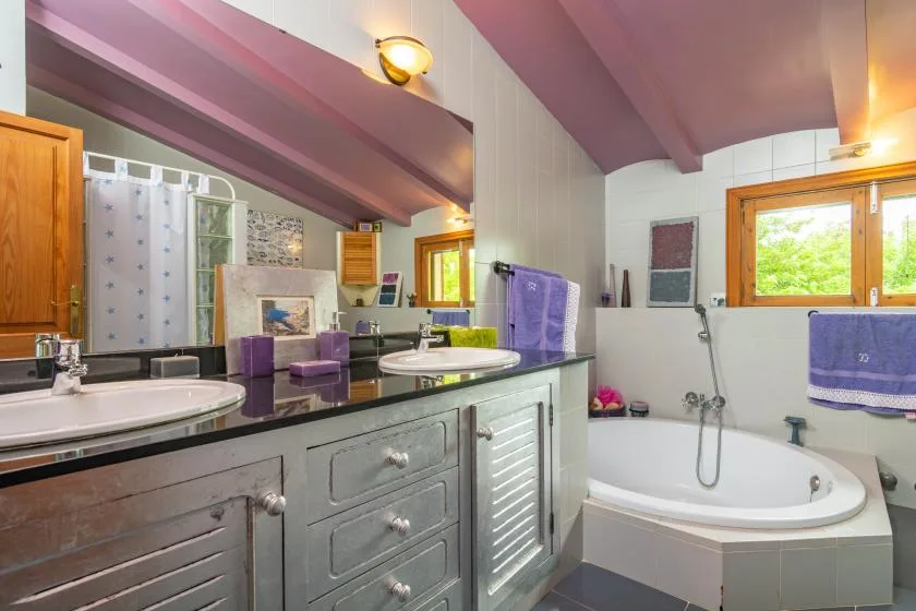 A bathroom with a long vanity and a bathtub beneath a sloped ceiling.