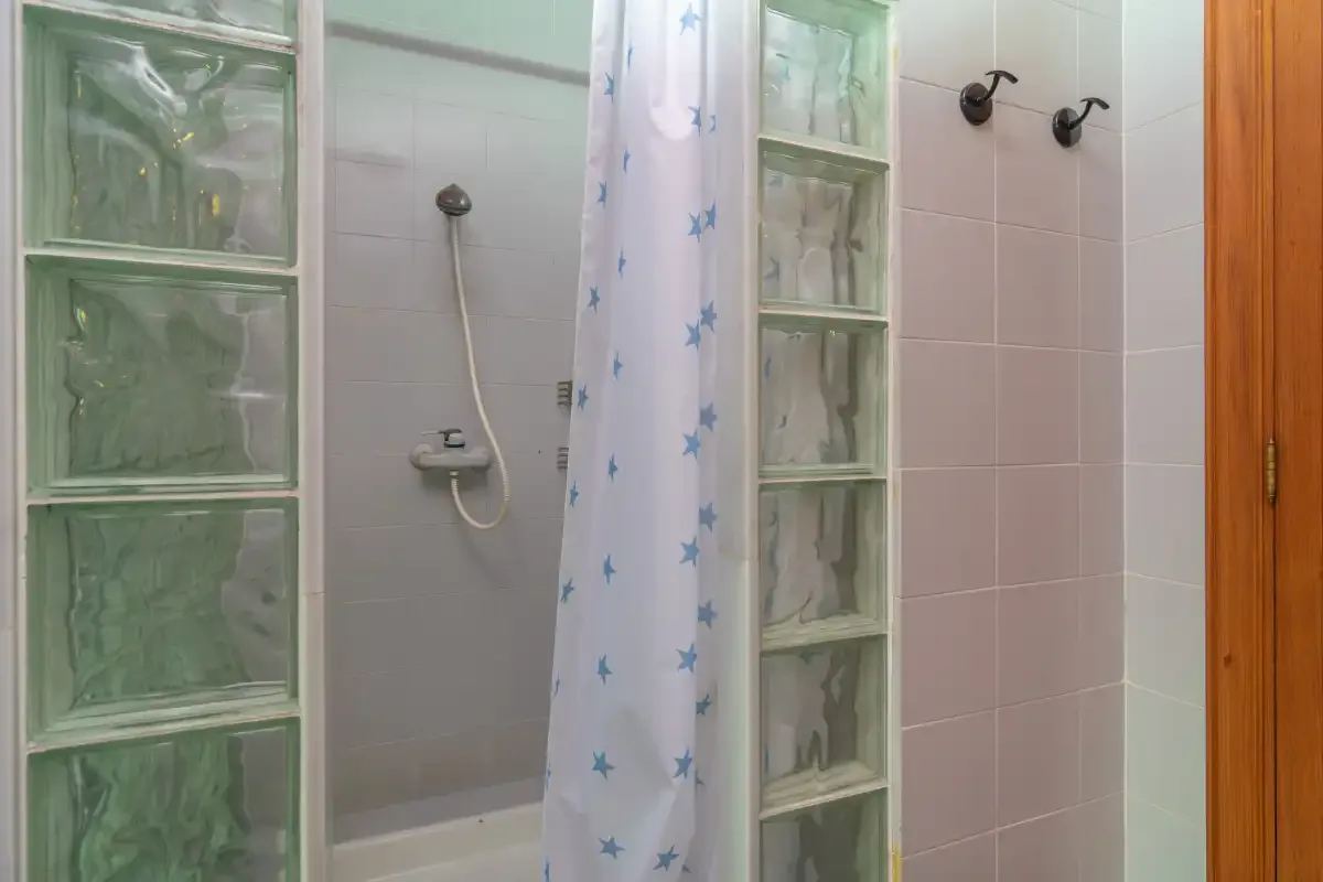 A tiled bathroom with a shower curtain and glass-block partitions.