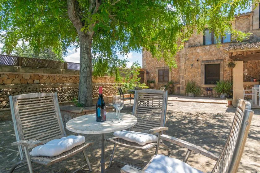 An outdoor patio with a table and seating beneath a leafy tree.
