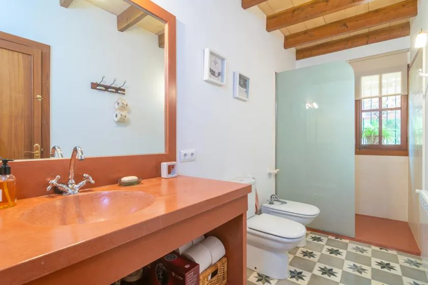 A bathroom with a long counter, sink, toilet, and shower area.