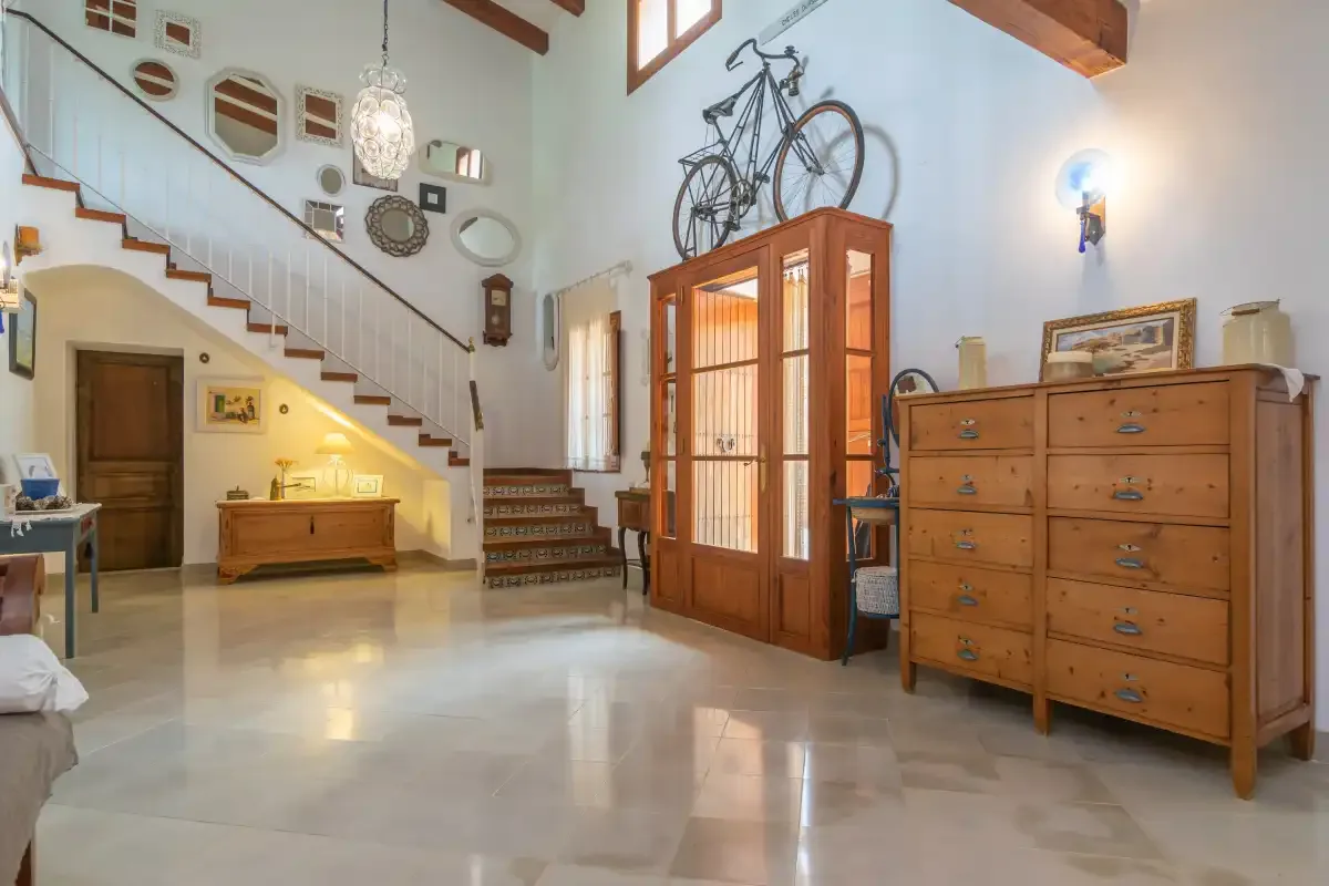 A bright interior room with a staircase and wooden furnishings.