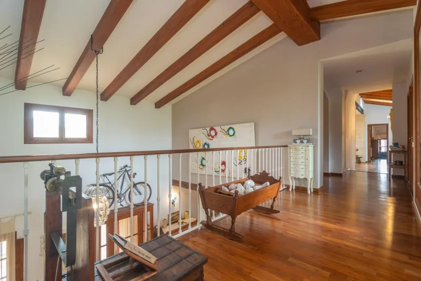 A wooden-floored interior hallway opens onto a landing with exposed ceiling beams.