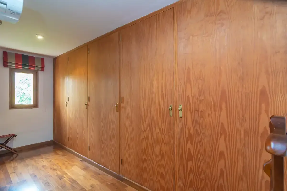 A room with a long row of wooden cabinets and a small window.