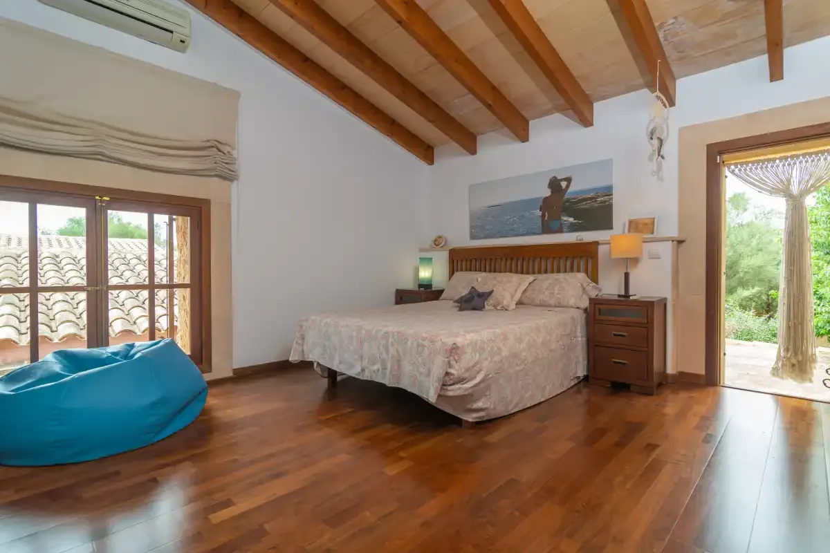 A bedroom with a double bed and wooden ceiling beams.