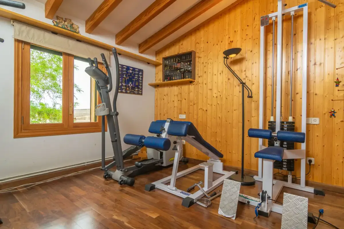 A home gym with exercise machines beside a window.