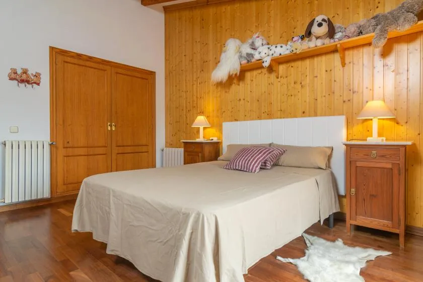A bedroom with a double bed, wooden headboard wall, and matching bedside tables.