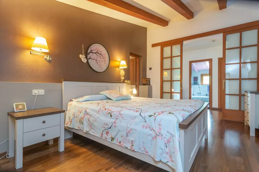 A bedroom with a double bed covered in floral bedding.