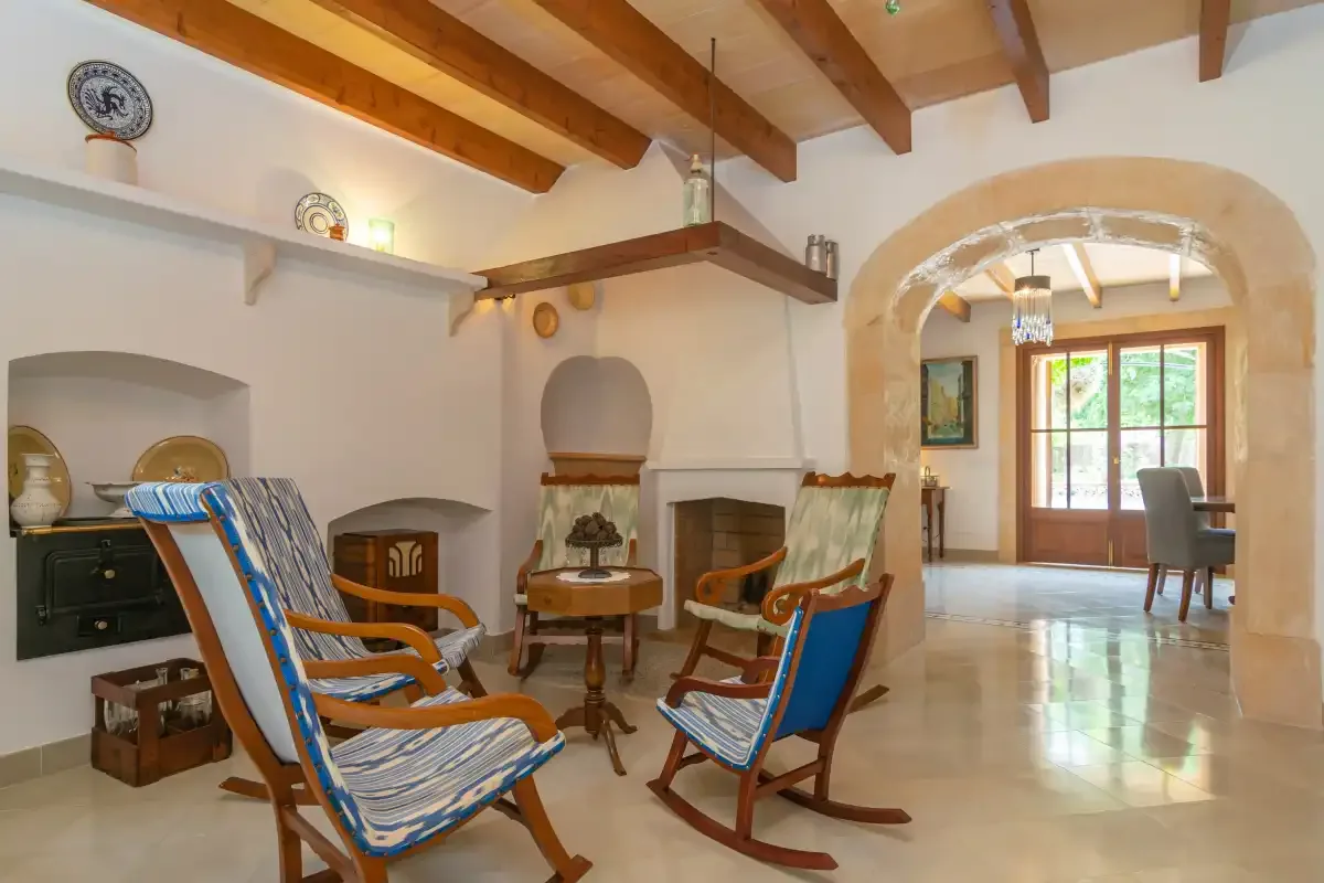 A living room with wooden seating and an arched opening to a dining area.