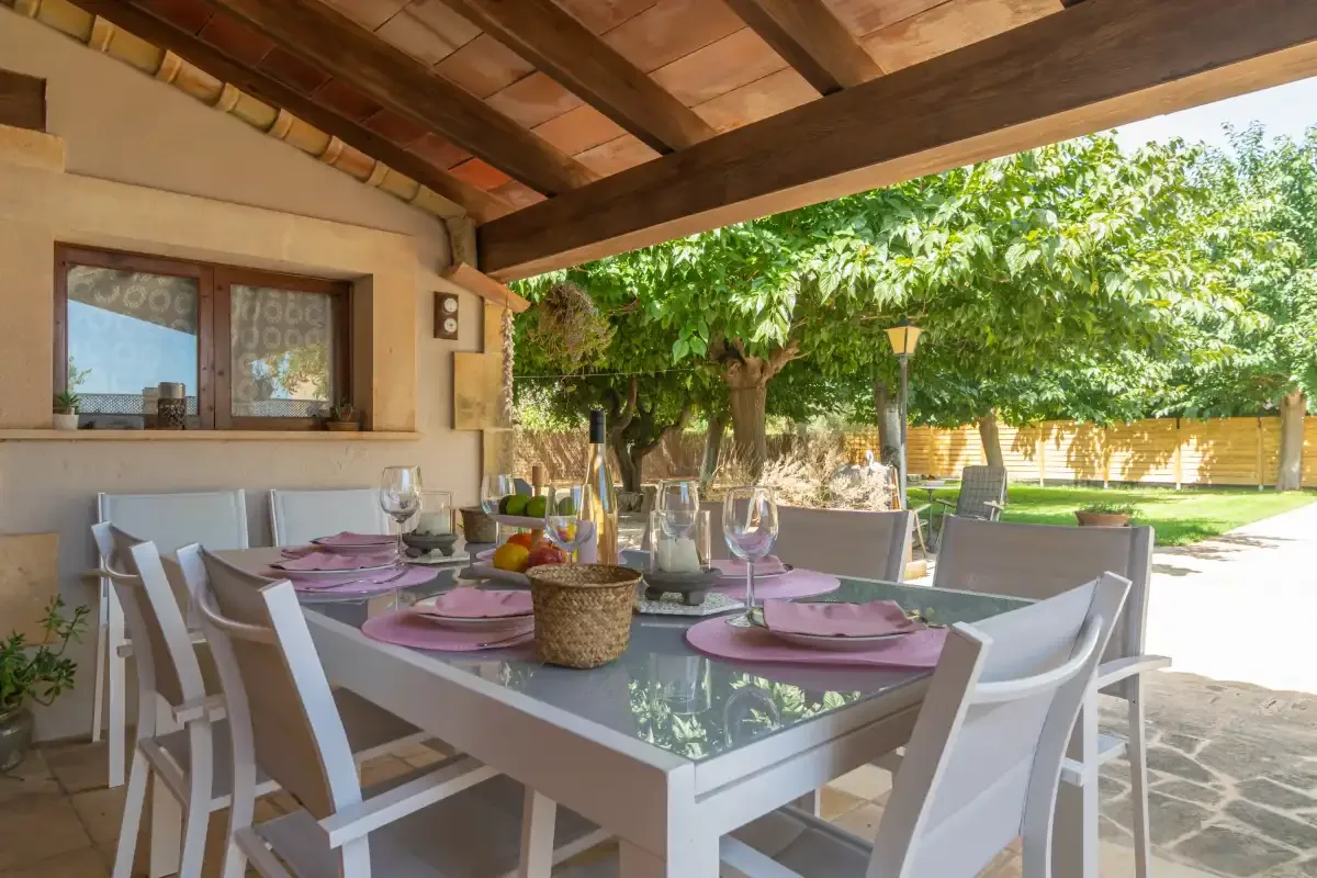 A covered outdoor dining area with a table set for a meal.