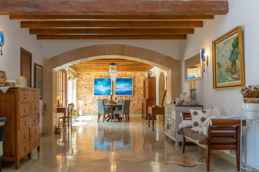 A dining and sitting room with a table beneath exposed wooden ceiling beams.