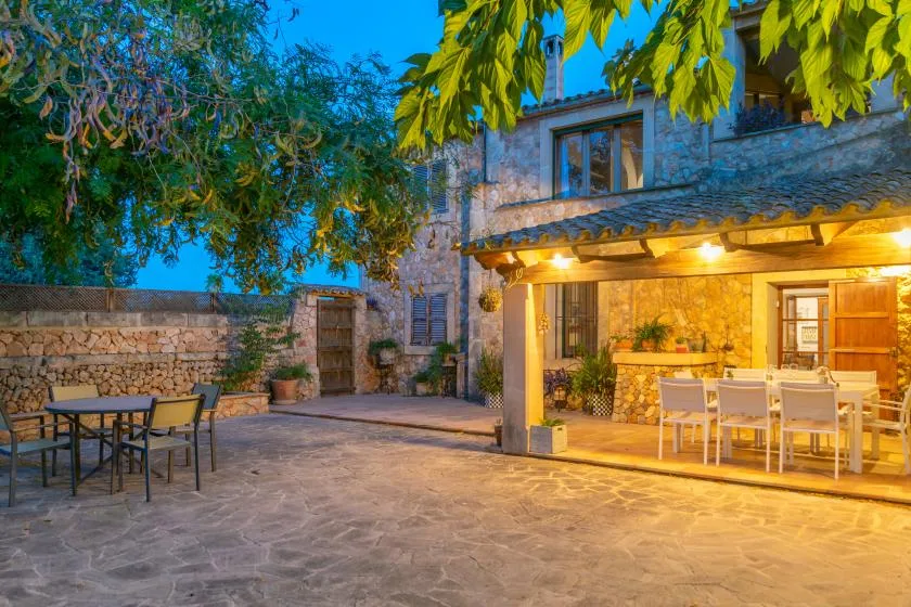 A stone courtyard with outdoor seating and a warmly lit covered dining area.