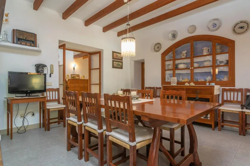 A dining room with wooden tables and chairs beneath exposed ceiling beams.