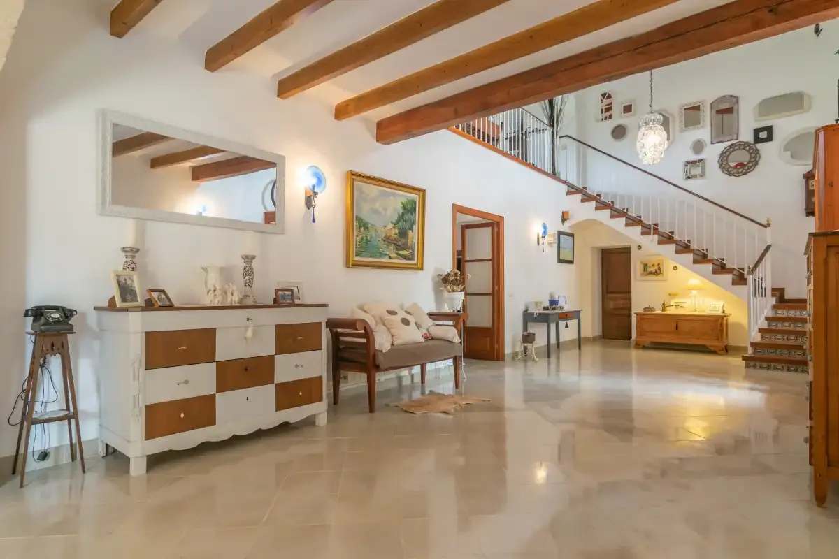 A spacious living room opens onto a staircase, with seating and a sideboard.