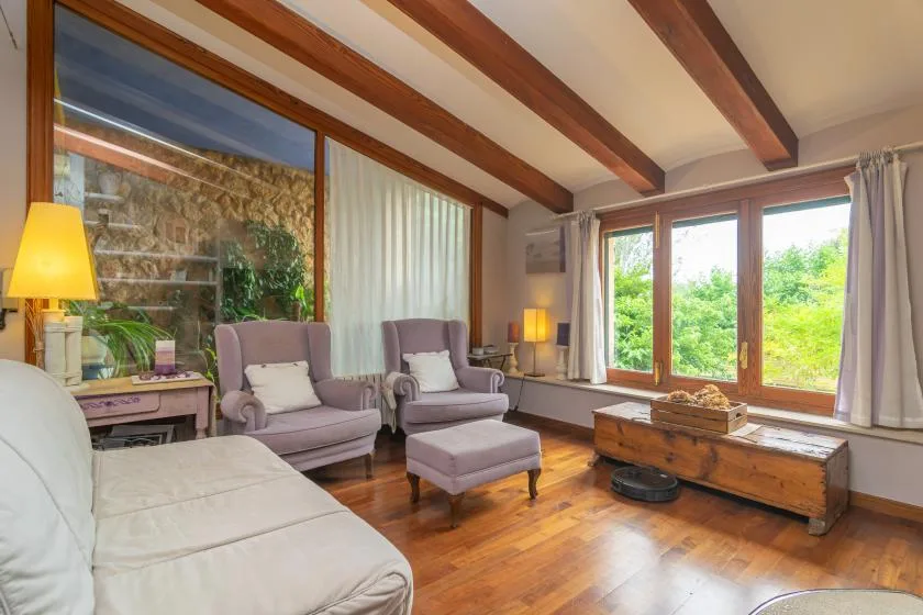 A living room with seating arranged beside large windows overlooking greenery.