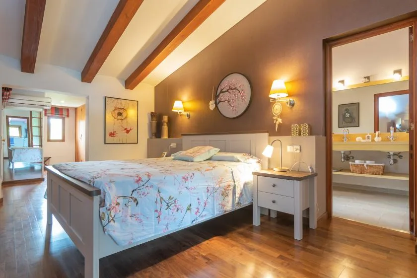 A bedroom with a large bed, bedside tables, and exposed ceiling beams.