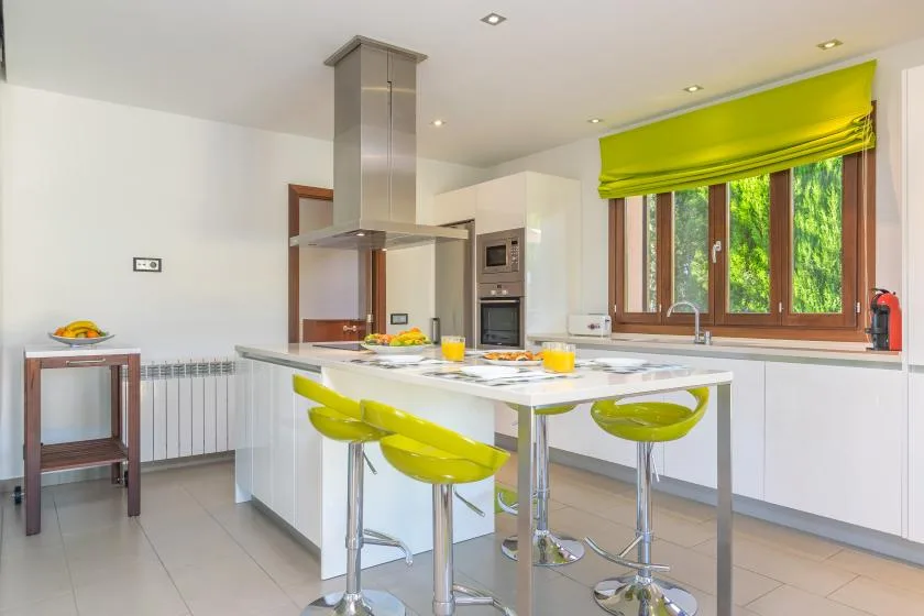 A bright kitchen with a central island and green bar seating.