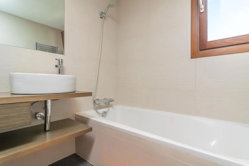 A bathroom with a bathtub, shower, and sink.