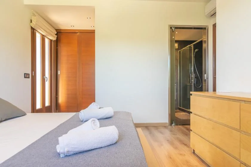 A bedroom with a bed, folded towels, and a doorway to the bathroom.