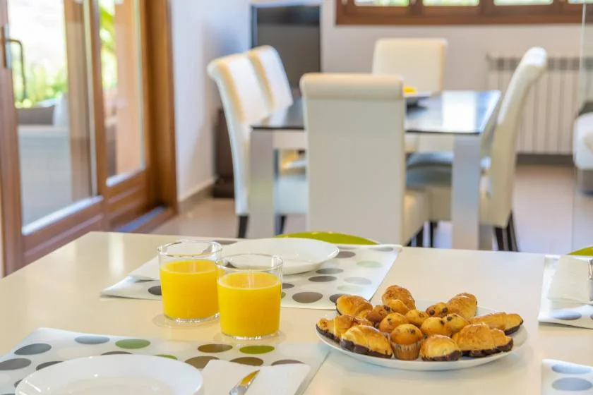 A dining area with a table set with juice and pastries.