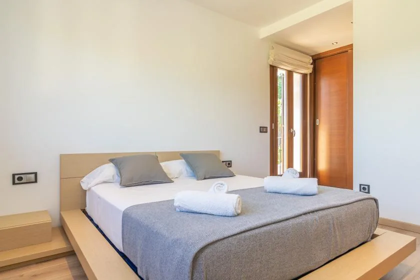 A bedroom with a neatly made bed and folded towels.