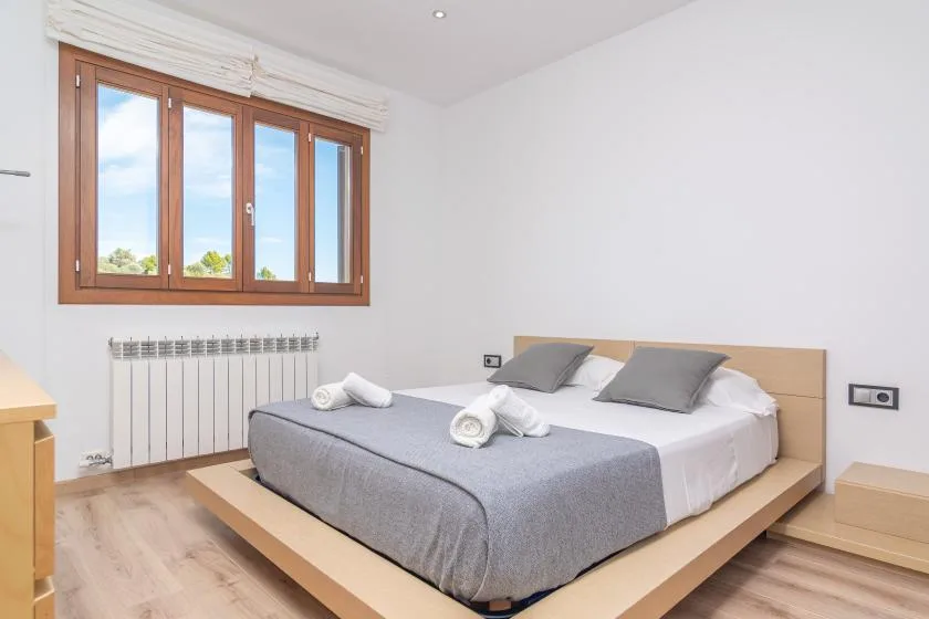 A bright bedroom with a low bed and a large wood-framed window.
