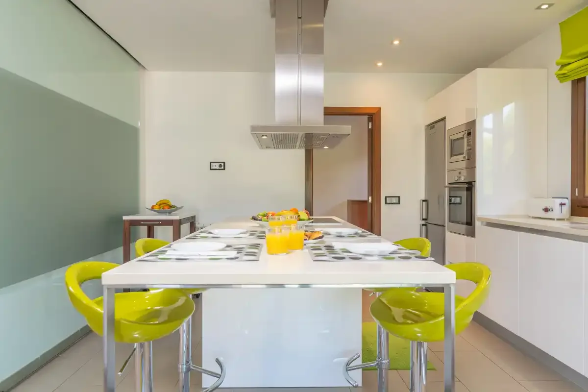 A modern kitchen with a long dining table and bright green seating.
