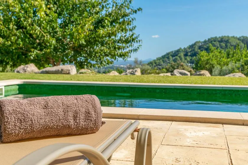 A swimming pool beside a paved deck, with a towel on nearby seating.