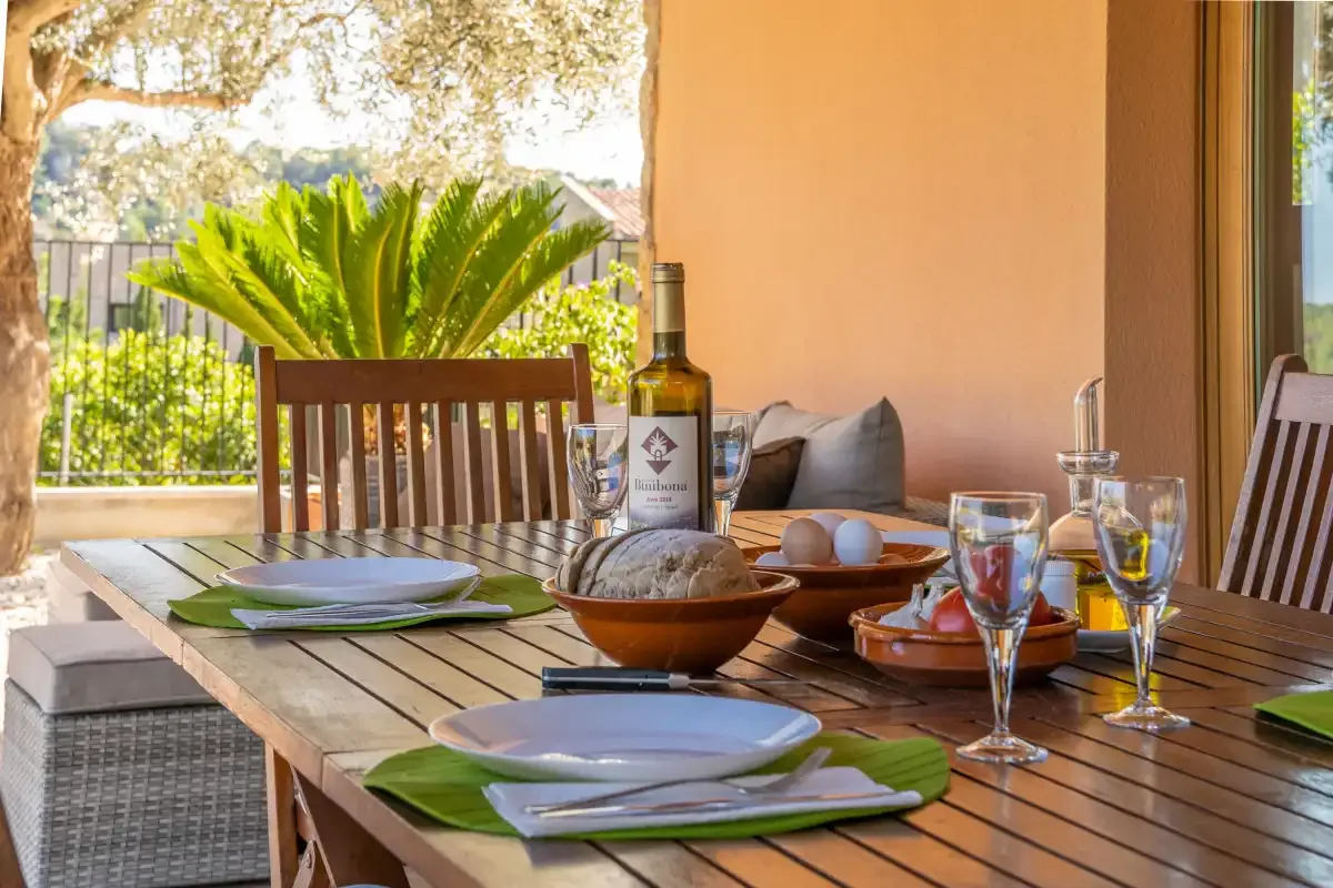 A patio dining table is set with plates, glasses, and food.