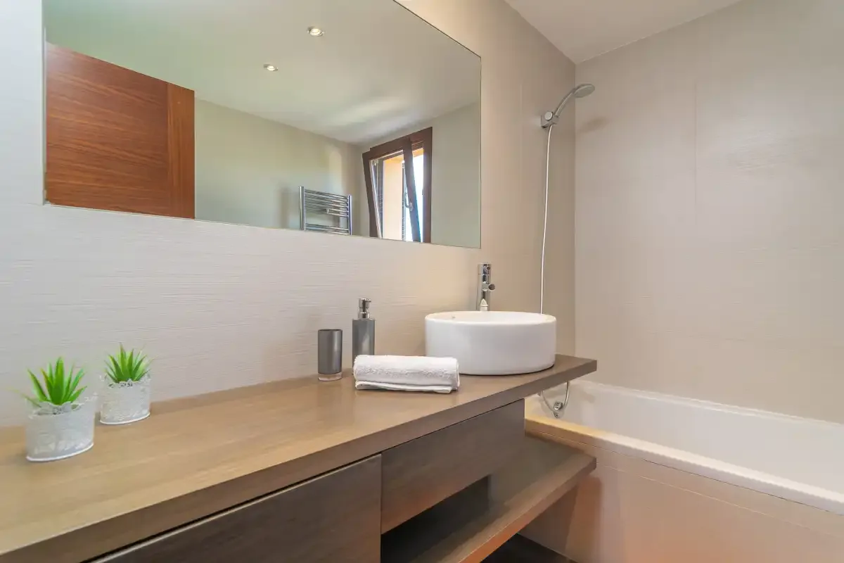 A bathroom vanity with a wide mirror and a vessel sink.