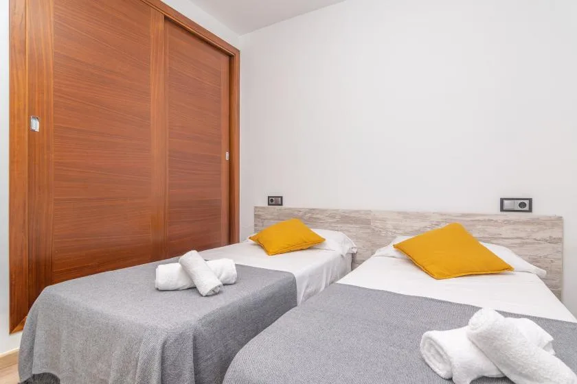 A bedroom with two single beds, gray covers, and yellow pillows.
